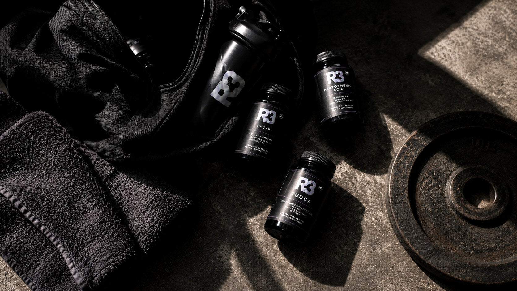 R3 supplement bottles arranged on a dark gym floor with clickable product hotspots